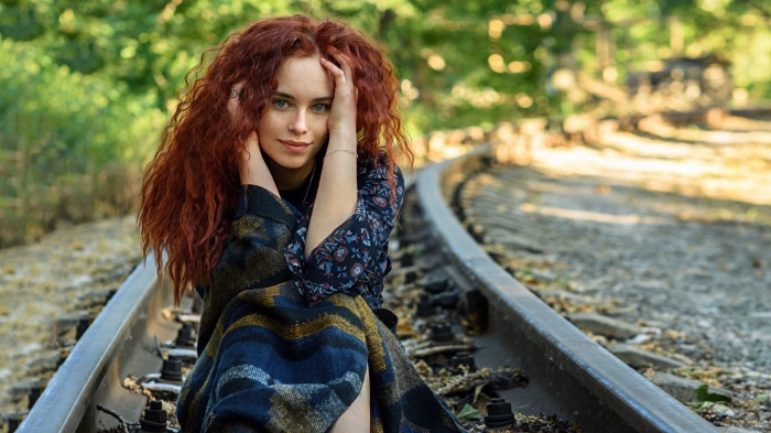 Redhead woman sitting on train tracks