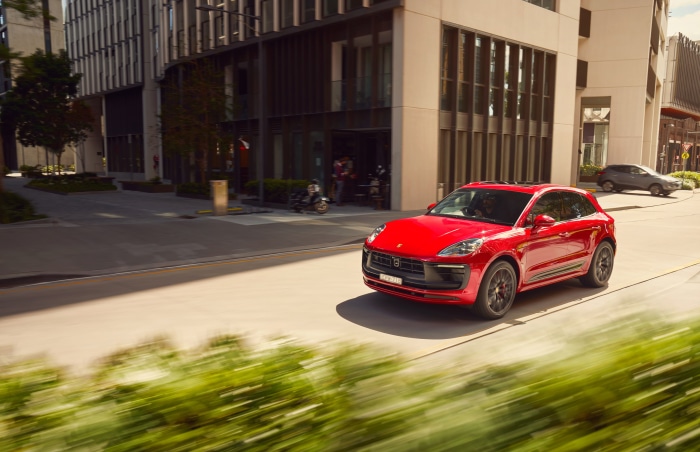 Red Porsche Macan GTS driving on a city street