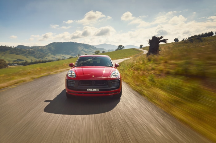 Red Porsche Macan GTS driving on a country road