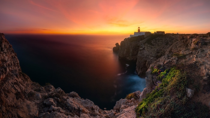 Lighthouse on cliffs at sunset over the ocean