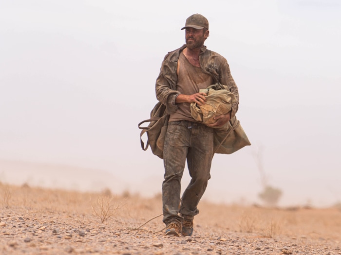 Man walking through a dusty landscape