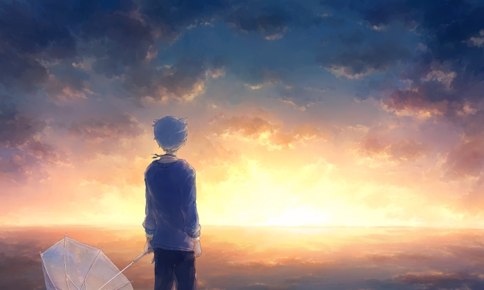 Boy with umbrella watching sunset over the ocean