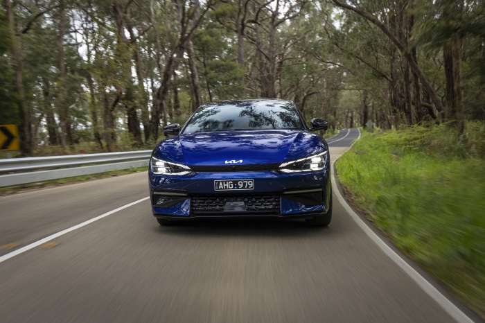 Blue Kia EV6 GT Line driving on a tree-lined road