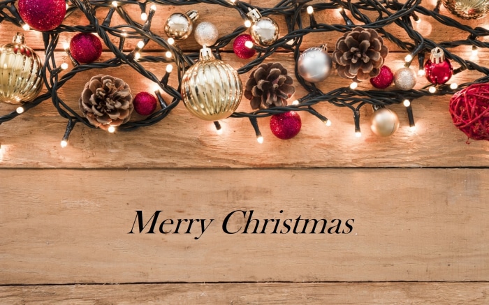 Christmas lights and ornaments on wooden background with Merry Christmas text