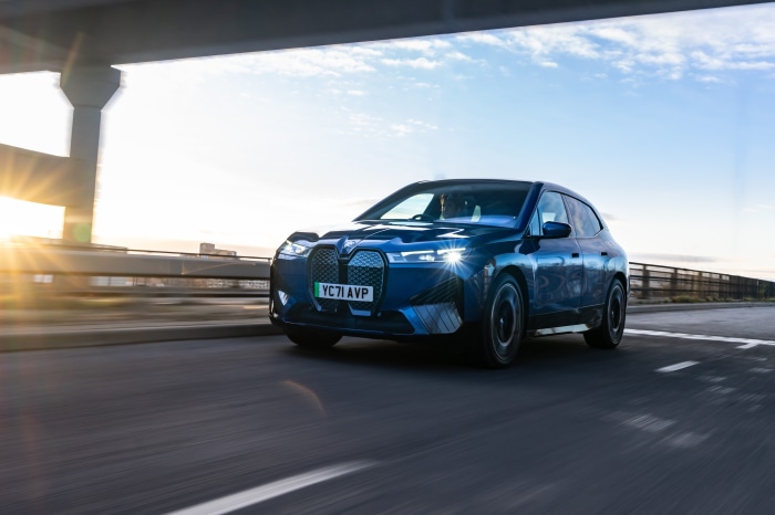 Blue BMW iX xDrive40 Sport driving on a bridge