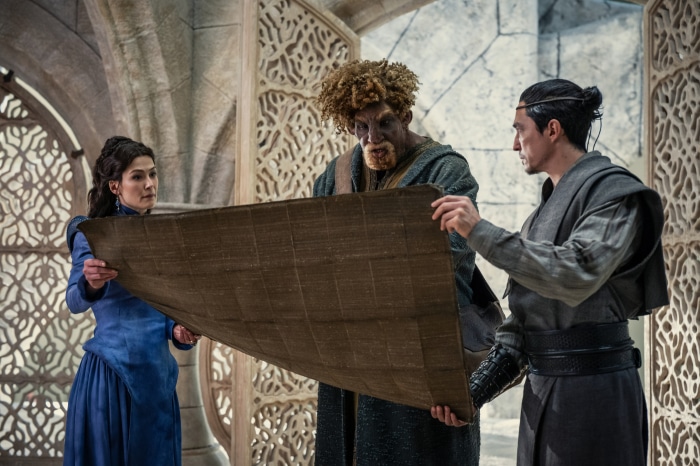 Moiraine, Lan, and Loial from The Wheel of Time examine a map