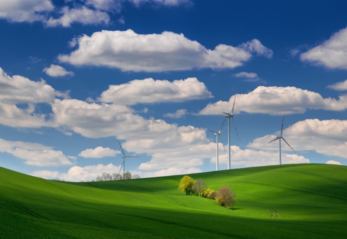 Wind turbines on green rolling hills under a blue sky