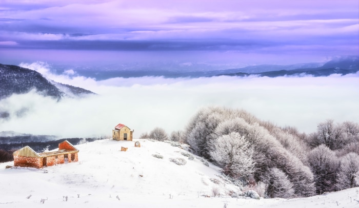 Winter landscape with abandoned buildings and sea of clouds