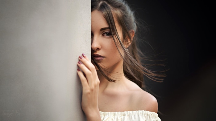 Woman peeking from behind a wall