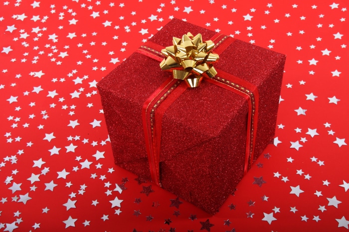 Red glitter gift box with gold bow on red star background 4K