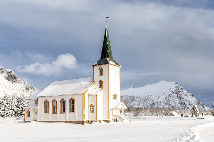 White church with green spire in snowy Lofoten Islands, Norway
