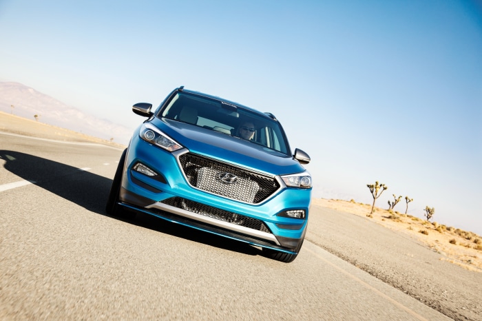 Blue Hyundai Tucson SUV driving on desert road