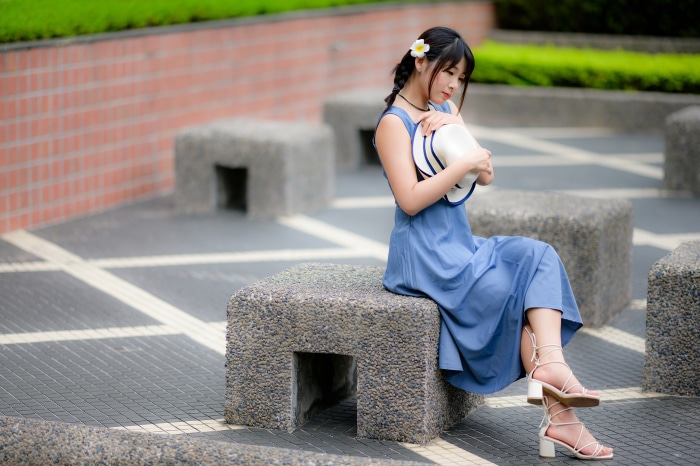 Asian woman in blue dress holding a hat