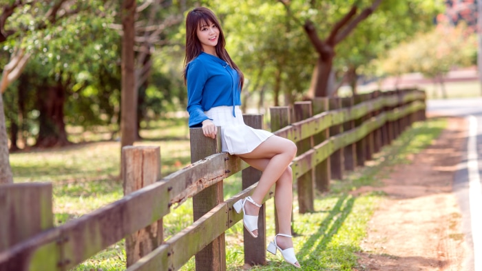 Asian woman sitting on a wooden fence