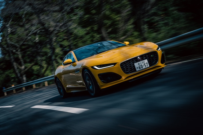Yellow Jaguar F-Type R Coupe driving on a road