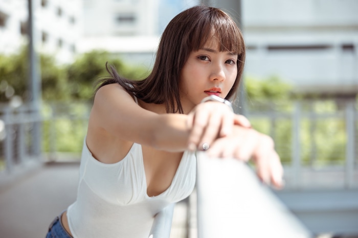 Asian woman in white top leaning on railing
