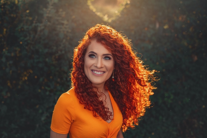 Woman with curly red hair in orange shirt