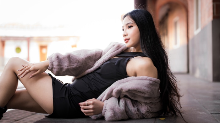 Asian woman with black hair in black dress and fur coat