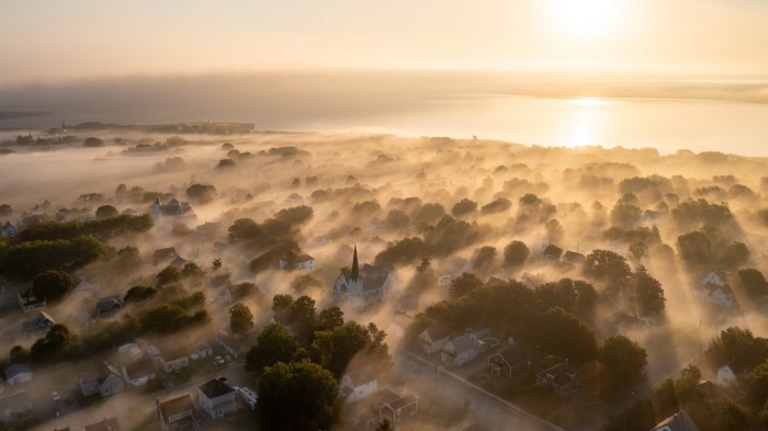 Aerial view of a foggy coastal town at sunrise