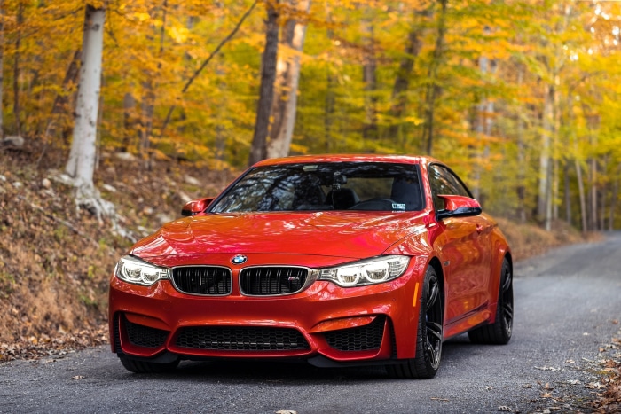 Red BMW M4 Coupe on a forest road in autumn