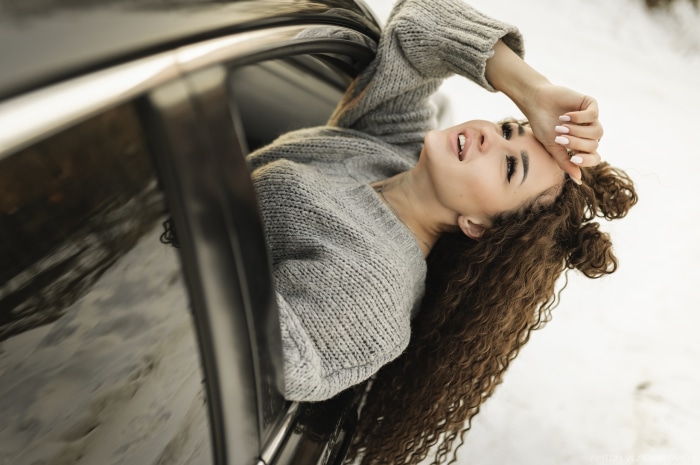 Woman with curly hair leaning out of a car window