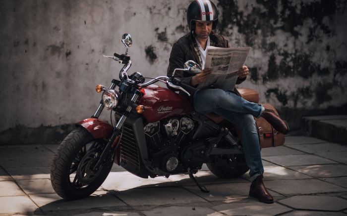 Man in Helmet Reading Newspaper on Indian Scout Motorcycle