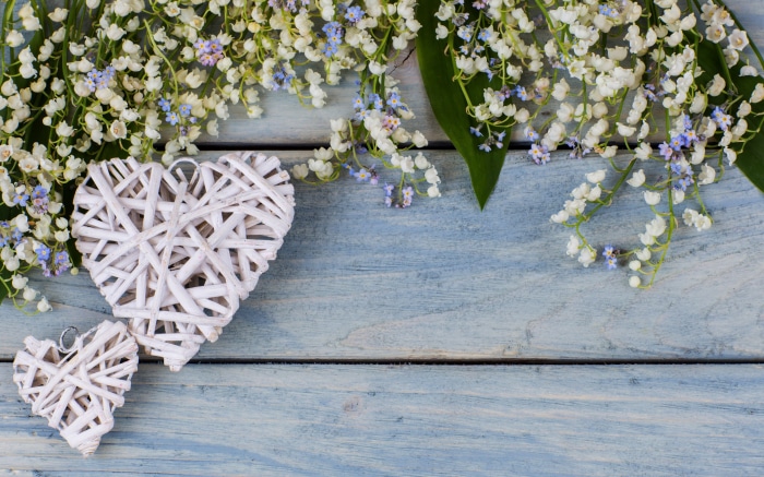 Lily of the valley flowers and white hearts on blue wood