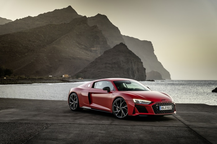 Red Audi R8 V10 parked by the sea with mountains