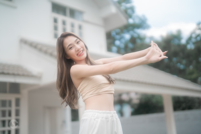 Young Asian woman stretching in front of a house