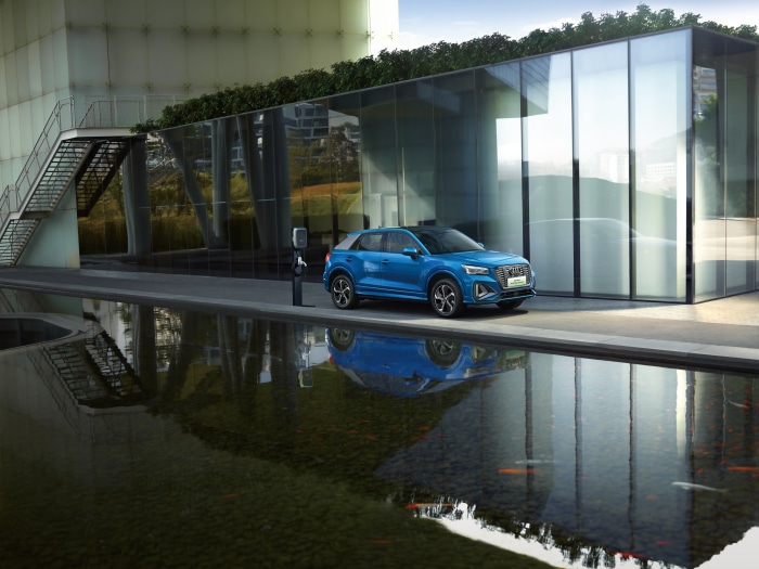 Blue Audi Q2 L e-tron SUV parked by modern building