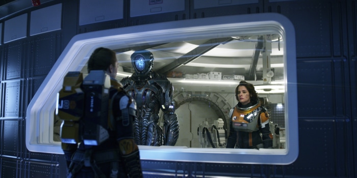 Robot and two people in spacesuits inside a spaceship