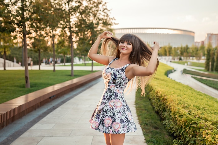 Brunette woman in a floral dress in a park
