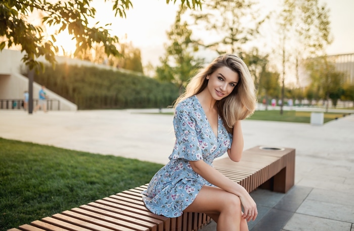Elena Korovaina in a blue floral dress sitting on a bench