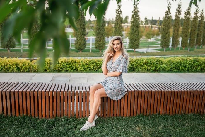 Elena Korovaina in a floral dress sitting on a bench