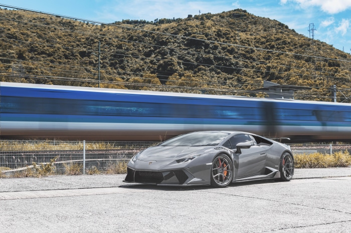 Gray Lamborghini Huracan parked near a moving train
