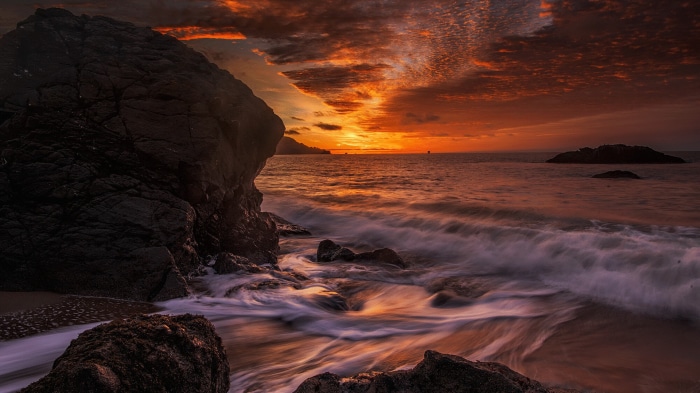 Sunset over the ocean with rocky shore