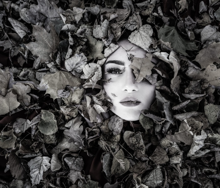 Woman's face emerging from black and white leaves