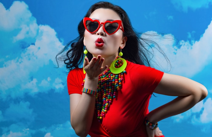 Woman with heart sunglasses blowing kiss