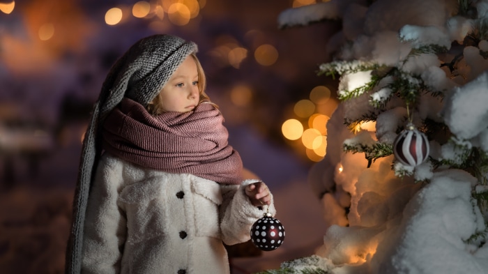 Girl in winter coat and scarf with Christmas ornament