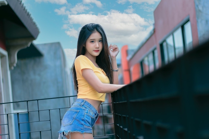 Young Asian woman in yellow crop top and denim shorts