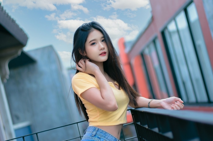 Young Asian woman in yellow crop top and jeans