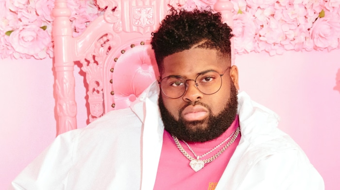 Man in pink and white outfit with glasses