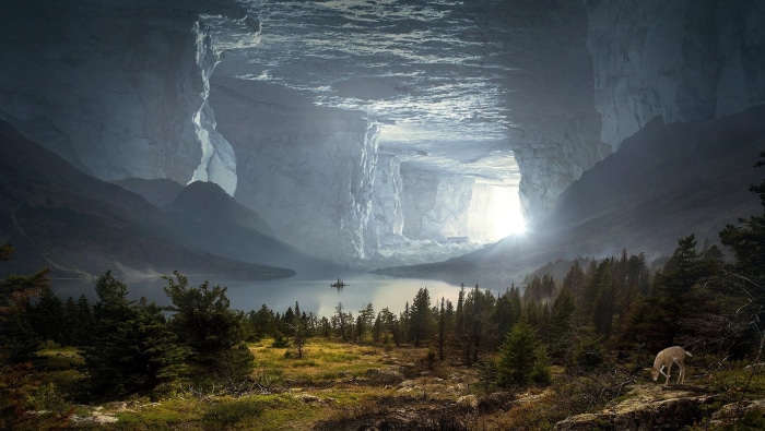 Vast cave opening with a lake and forest