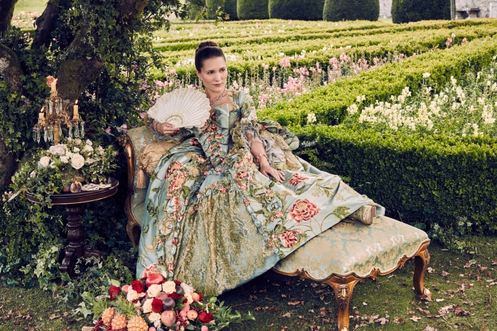Woman in historical dress with fan in garden