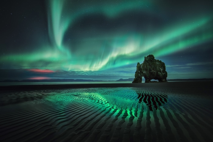 Aurora Borealis over Hvitserkur rock formation on beach