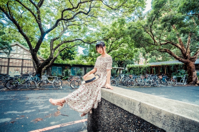 Asian woman in floral dress sitting near bicycles