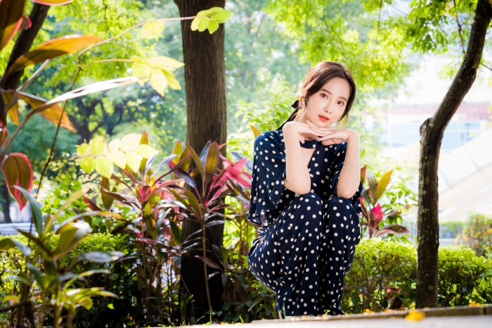 Asian woman in polka dot dress in garden