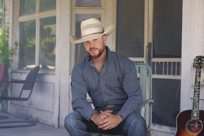 Cody Johnson sitting on a porch with a guitar