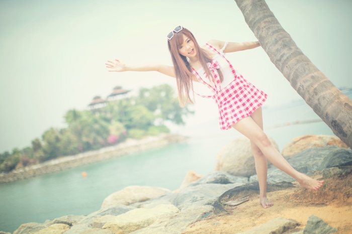 Asian girl in pink checkered dress by palm tree