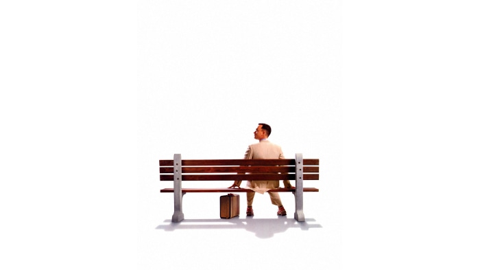 Forrest Gump sitting on a bench with a suitcase